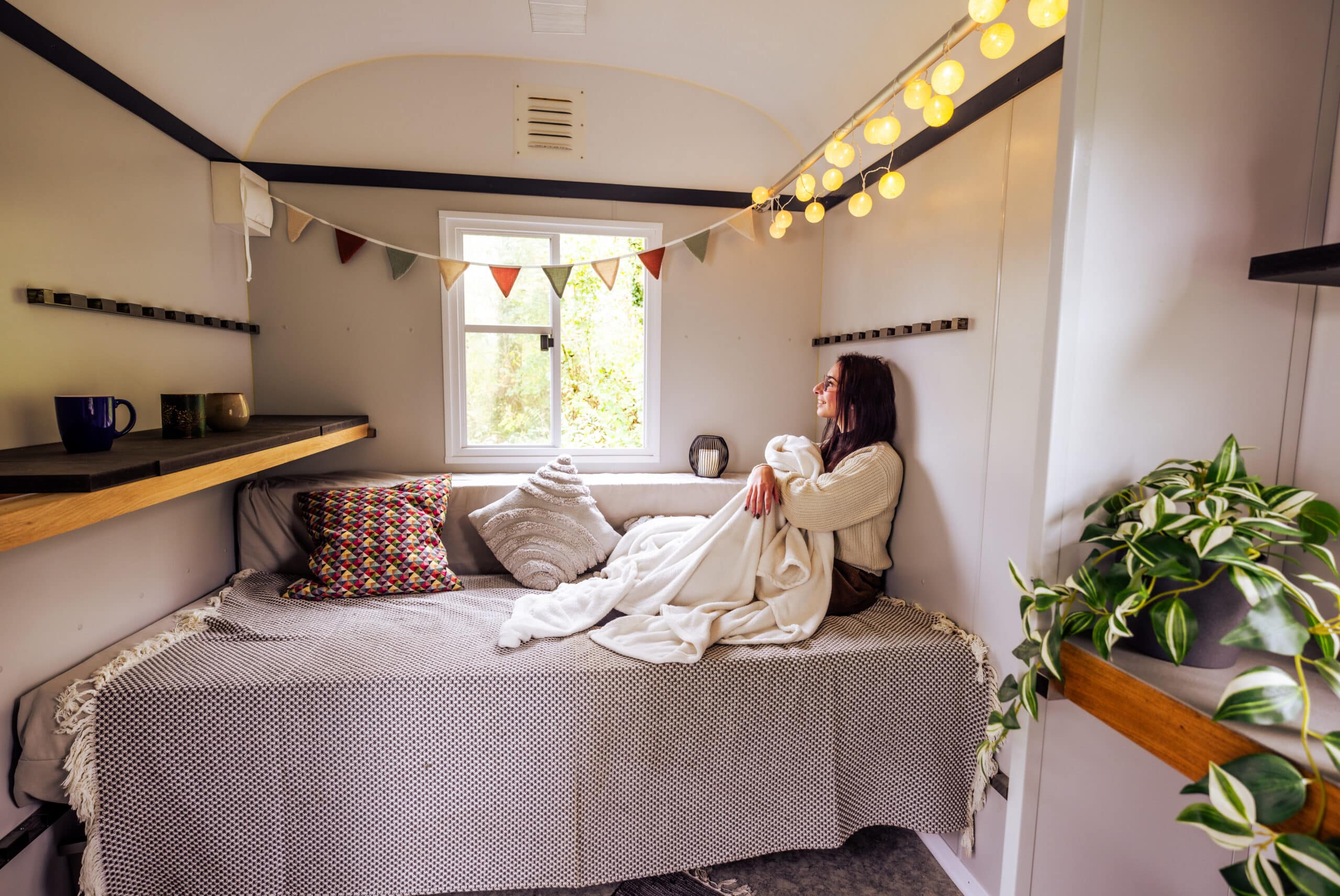 Bauwagen im Garten: Frau sitzt gemütlich auf dem Sofa im Wagen
