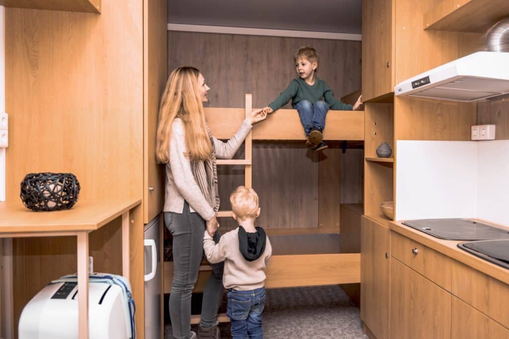 Frau mit zwei Kindern steht im Bauwagen.