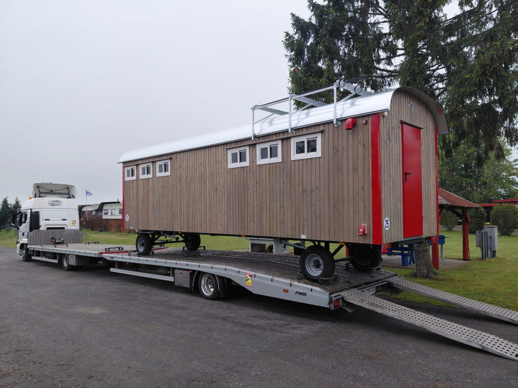 Vom Bauwagen zum Sanitärhaus: Sanitätswagen mit natürlicher Lärchenholzfassade und roten Akzenten